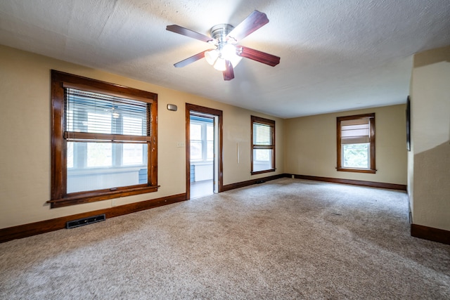carpeted spare room featuring ceiling fan, a healthy amount of sunlight, and a textured ceiling