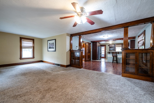 unfurnished living room featuring ceiling fan, dark hardwood / wood-style flooring, and a textured ceiling