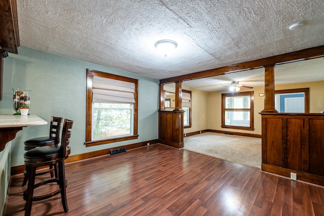 dining room with ceiling fan, dark hardwood / wood-style flooring, a textured ceiling, and decorative columns