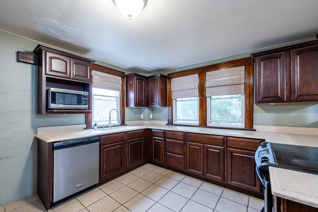 kitchen featuring dark brown cabinets, light tile patterned floors, sink, and appliances with stainless steel finishes