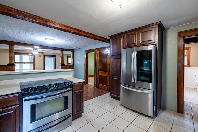 kitchen with appliances with stainless steel finishes, a textured ceiling, dark brown cabinetry, ceiling fan, and light tile patterned floors