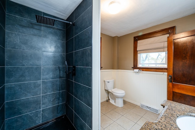bathroom with tiled shower, tile patterned floors, vanity, and toilet
