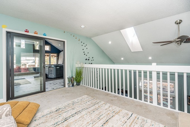 interior space with a textured ceiling, vaulted ceiling with skylight, and carpet