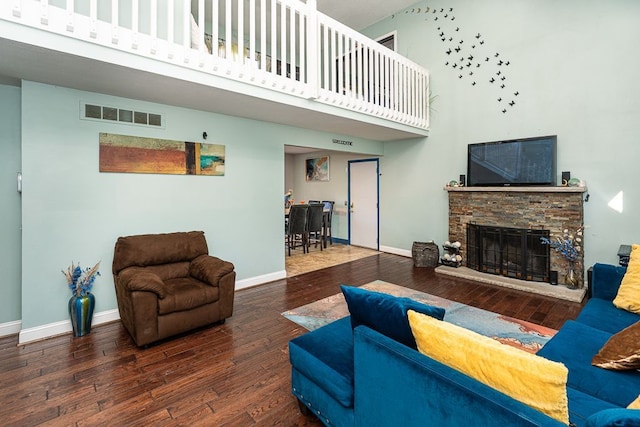 living room with a high ceiling, dark hardwood / wood-style flooring, and a fireplace