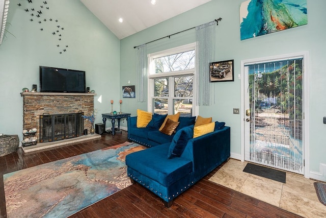 living room featuring high vaulted ceiling, wood-type flooring, and a stone fireplace