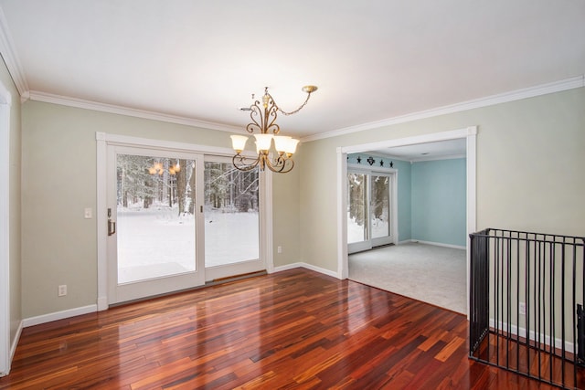 spare room with dark wood-type flooring, an inviting chandelier, and ornamental molding