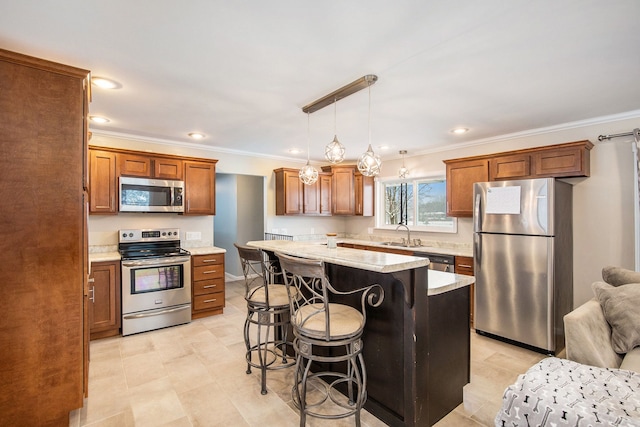 kitchen with a center island, sink, stainless steel appliances, decorative light fixtures, and a breakfast bar