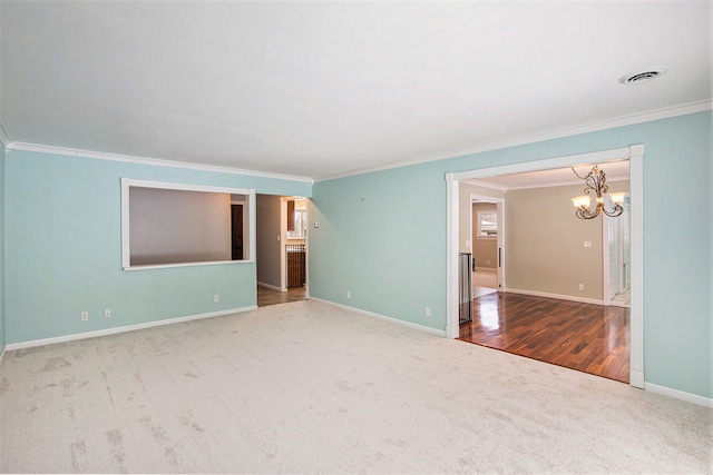 spare room with crown molding, carpet, and an inviting chandelier