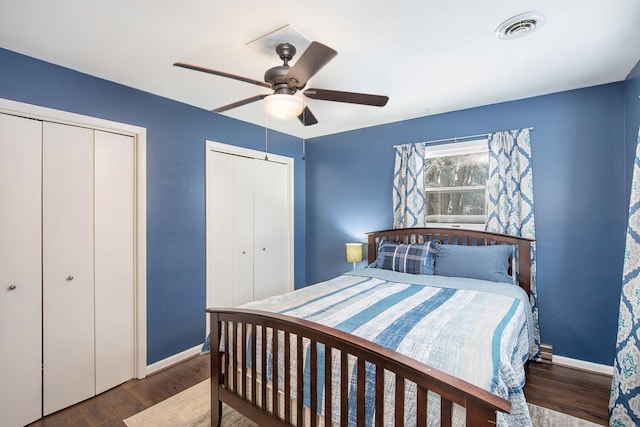 bedroom featuring ceiling fan, dark hardwood / wood-style floors, and two closets