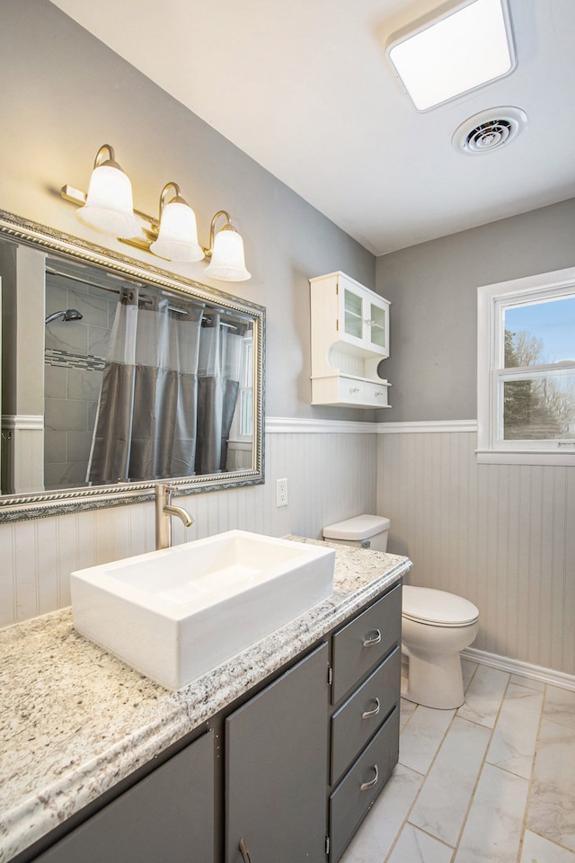 bathroom with toilet, vanity, and a shower with shower curtain