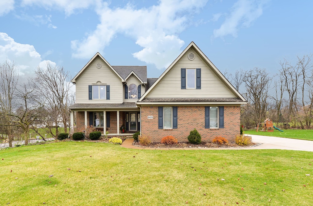 view of property featuring covered porch and a front yard