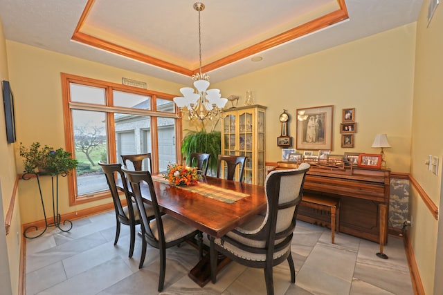 dining area featuring an inviting chandelier and a raised ceiling