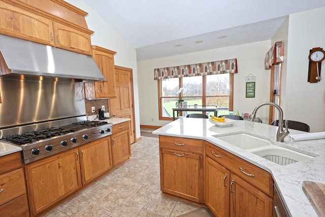 kitchen featuring stainless steel gas stovetop, sink, vaulted ceiling, light stone counters, and extractor fan