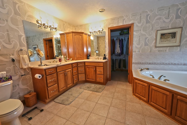 bathroom featuring vanity, a bath, tile patterned floors, toilet, and a textured ceiling