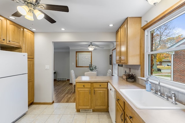 kitchen featuring sink, backsplash, kitchen peninsula, white appliances, and light tile patterned flooring