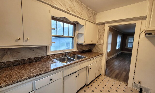931 Hughes Ave, Flint, MI 48503 - kitchen featuring a sink, dark countertops, white cabinets, tasteful backsplash, and light flooring