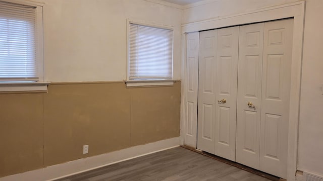 931 Hughes Ave, Flint, MI 48503 - unfurnished bedroom with wood finished floors, a closet, and multiple windows