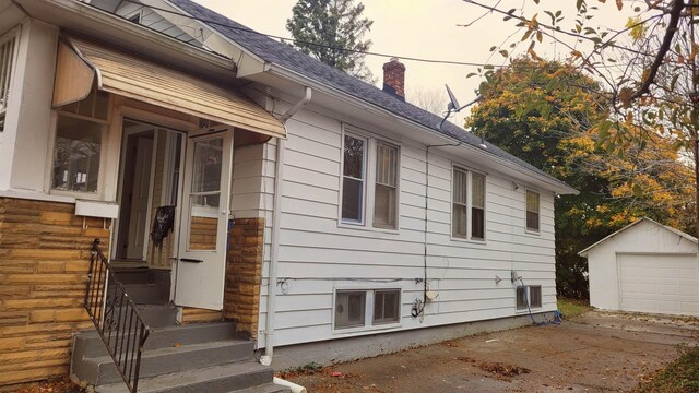 931 Hughes Ave, Flint, MI 48503 - view of property exterior featuring an outdoor structure, a chimney, roof with shingles, a garage, and concrete driveway