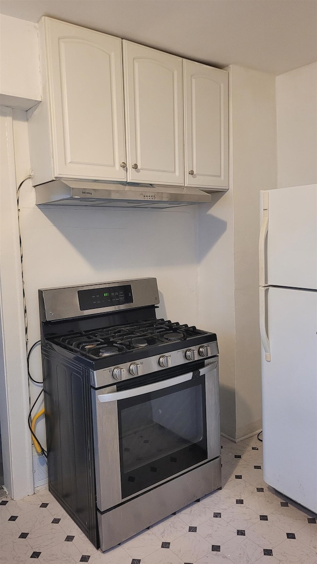 931 Hughes Ave, Flint, MI 48503 - kitchen featuring gas range, freestanding refrigerator, white cabinets, under cabinet range hood, and light floors