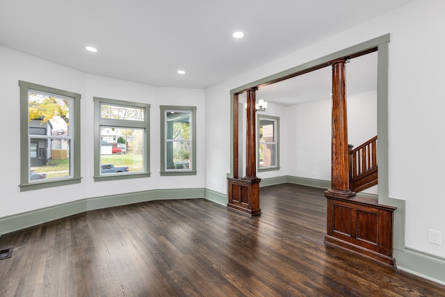 unfurnished living room featuring a wealth of natural light, dark wood-type flooring, and a notable chandelier