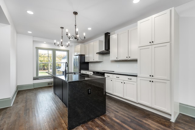 kitchen featuring white cabinetry, a kitchen island with sink, wall chimney exhaust hood, and hanging light fixtures