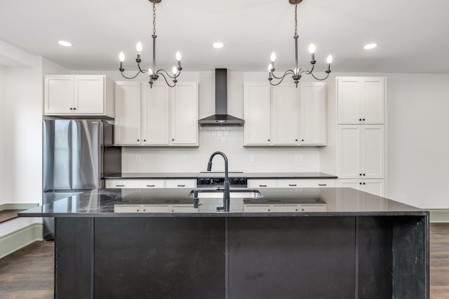 kitchen with a kitchen island with sink, wall chimney range hood, and an inviting chandelier