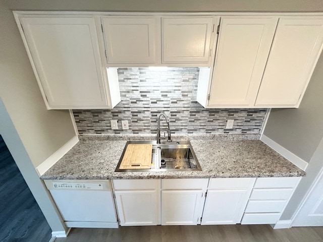 kitchen with dark wood-type flooring, white cabinets, white dishwasher, sink, and light stone countertops