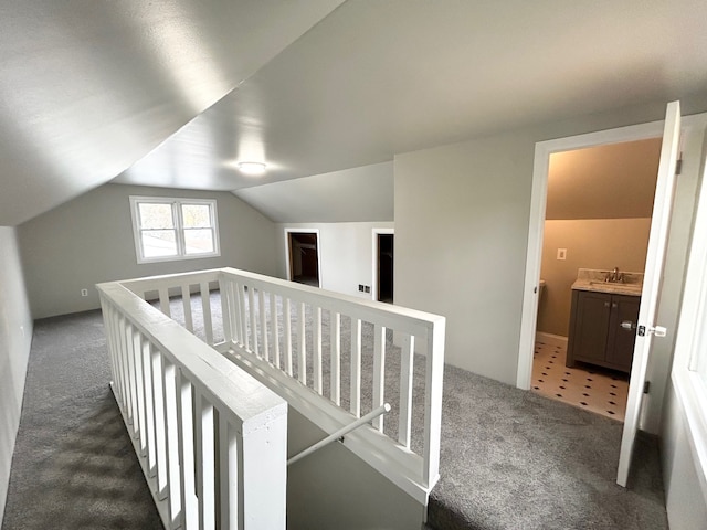 hall with dark carpet, lofted ceiling, and sink