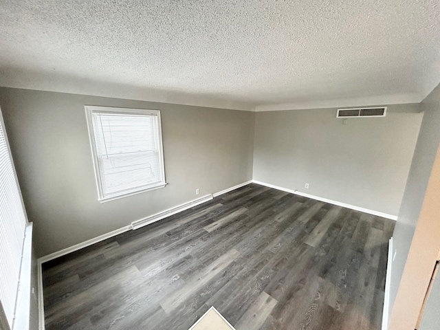 spare room featuring baseboard heating, a textured ceiling, and dark hardwood / wood-style floors