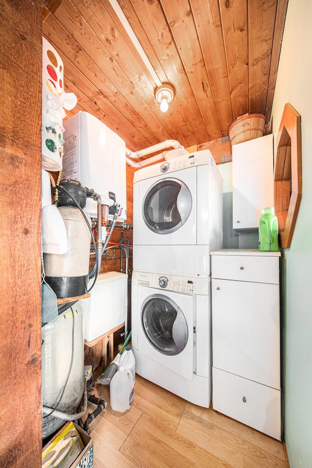 clothes washing area featuring wood ceiling, stacked washer / dryer, cabinets, and light hardwood / wood-style floors