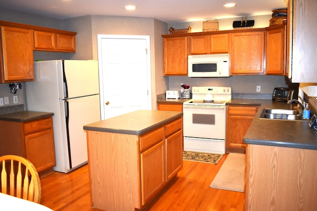 kitchen featuring white appliances, light hardwood / wood-style floors, a kitchen island, and sink