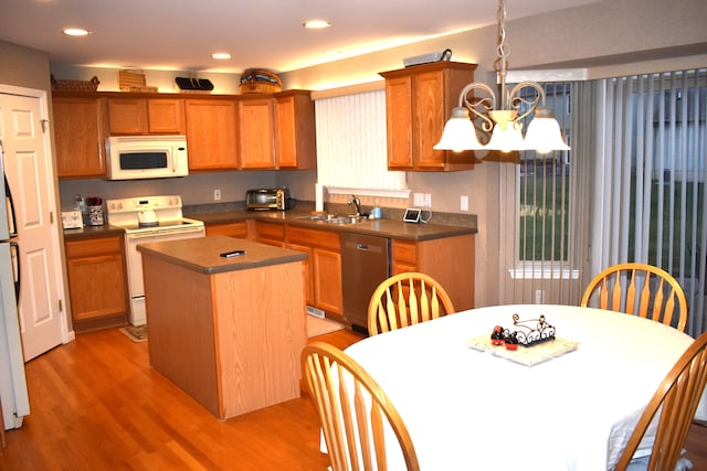 kitchen featuring sink, light hardwood / wood-style flooring, a notable chandelier, white appliances, and a kitchen island