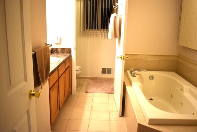 bathroom featuring tiled tub, tile patterned flooring, vanity, and toilet