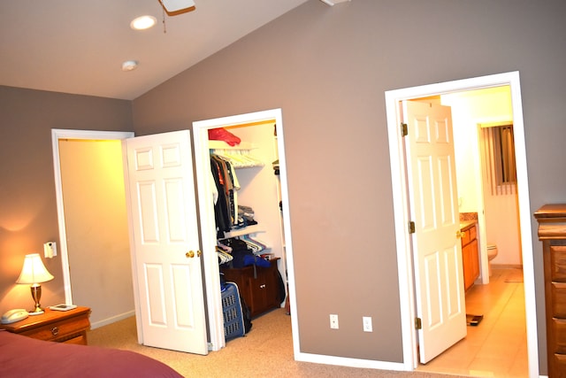 bedroom with light carpet, ensuite bath, vaulted ceiling, a spacious closet, and a closet