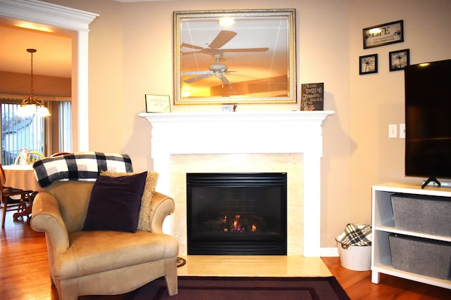 living area featuring ceiling fan with notable chandelier and hardwood / wood-style flooring