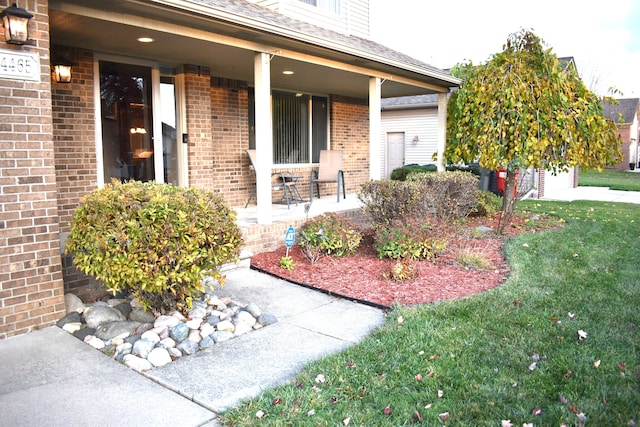 view of exterior entry featuring a porch and a yard