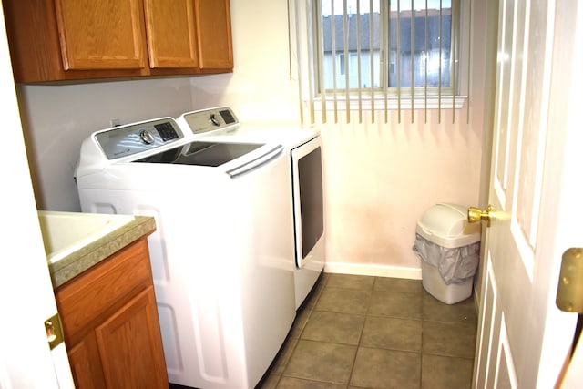 clothes washing area featuring cabinets, independent washer and dryer, and dark tile patterned floors