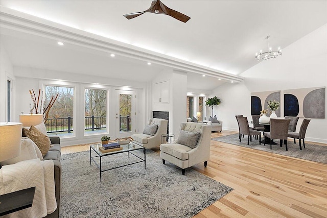 living room featuring lofted ceiling with beams, light wood-type flooring, and ceiling fan with notable chandelier