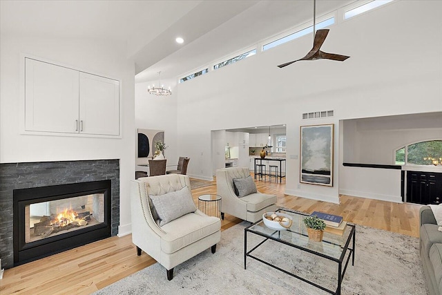 living room featuring a fireplace, light hardwood / wood-style flooring, high vaulted ceiling, and a notable chandelier