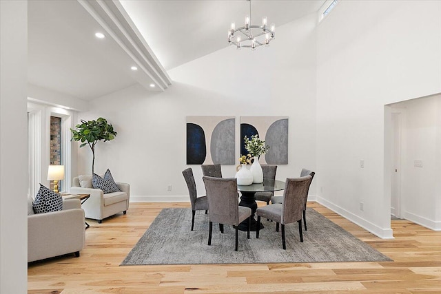 dining area featuring light hardwood / wood-style floors, high vaulted ceiling, and a notable chandelier