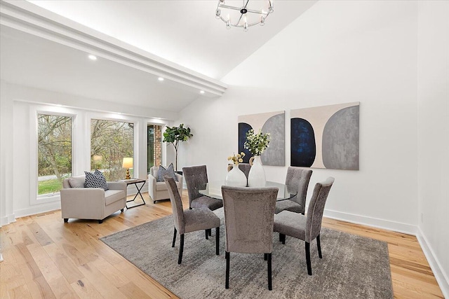 dining area with vaulted ceiling with beams, light hardwood / wood-style floors, and an inviting chandelier