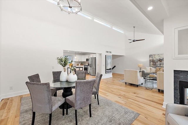 dining room featuring a towering ceiling, light hardwood / wood-style flooring, and ceiling fan