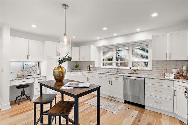 kitchen with stainless steel dishwasher, sink, decorative light fixtures, light hardwood / wood-style flooring, and white cabinetry