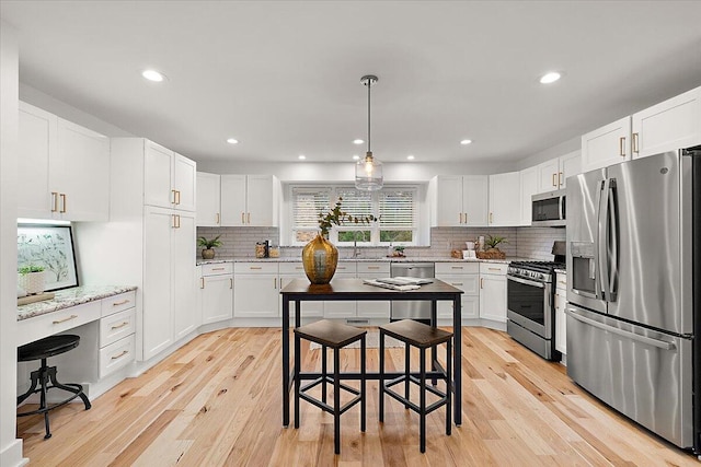 kitchen featuring white cabinetry, a kitchen bar, light wood-type flooring, and appliances with stainless steel finishes