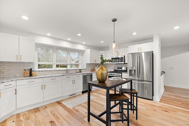 kitchen with decorative backsplash, white cabinets, stainless steel appliances, and light wood-type flooring