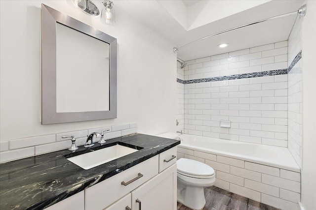 full bathroom with vanity, hardwood / wood-style flooring, toilet, and tiled shower / bath