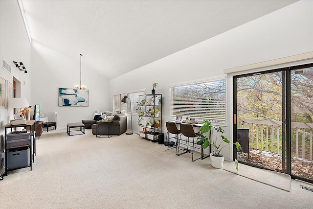 interior space with light carpet, a chandelier, high vaulted ceiling, and a healthy amount of sunlight