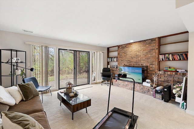 living room with built in shelves, light colored carpet, and a brick fireplace