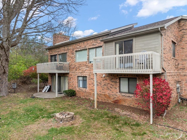 rear view of house featuring a balcony, a patio, and a fire pit