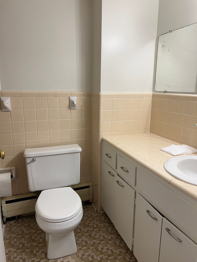 bathroom featuring vanity, toilet, tile walls, and a baseboard heating unit